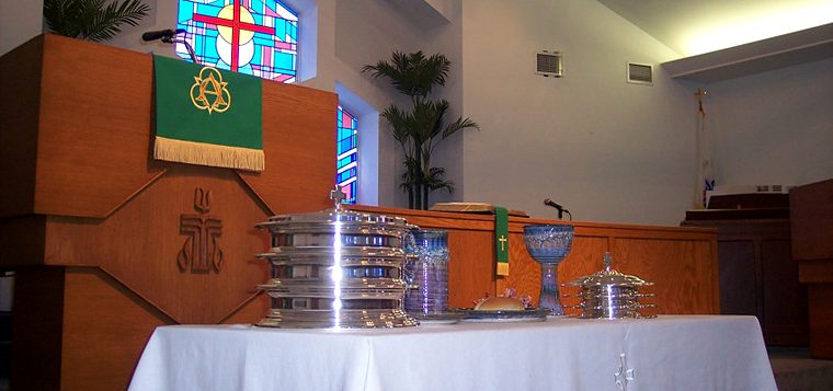The communion table set with silver, before the chancel windows