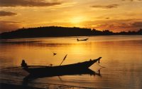 Picture of fishing boat with sunset sky behind it.